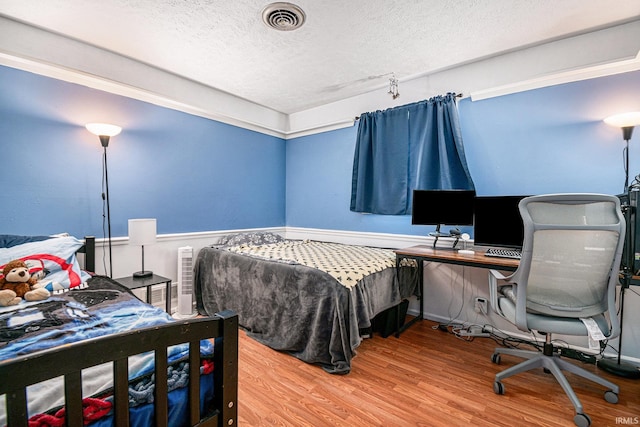 bedroom with hardwood / wood-style floors and a textured ceiling