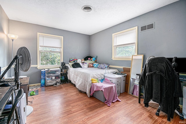 bedroom featuring a textured ceiling and light hardwood / wood-style floors