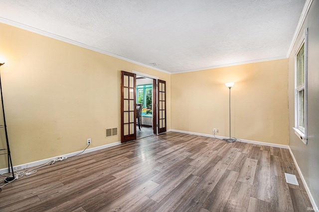 unfurnished room featuring french doors, crown molding, a textured ceiling, and hardwood / wood-style floors