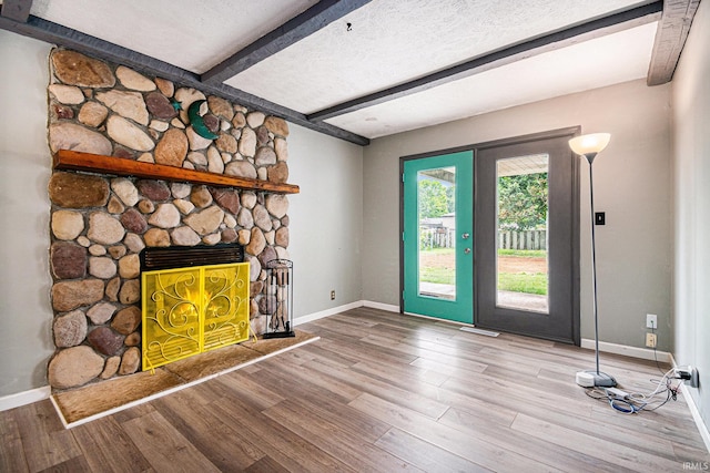 unfurnished living room with french doors, hardwood / wood-style floors, beam ceiling, and a fireplace