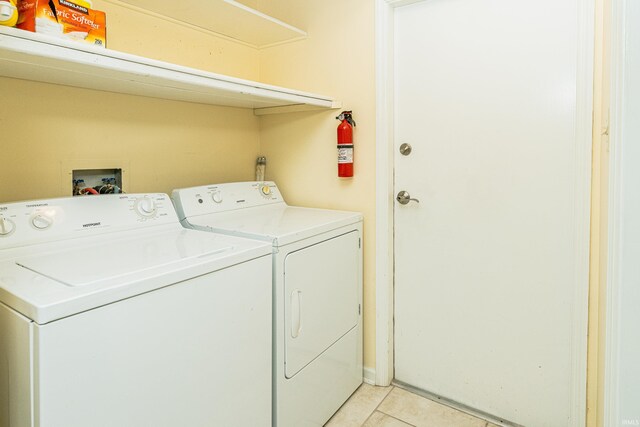 clothes washing area featuring light tile patterned floors and washer and clothes dryer