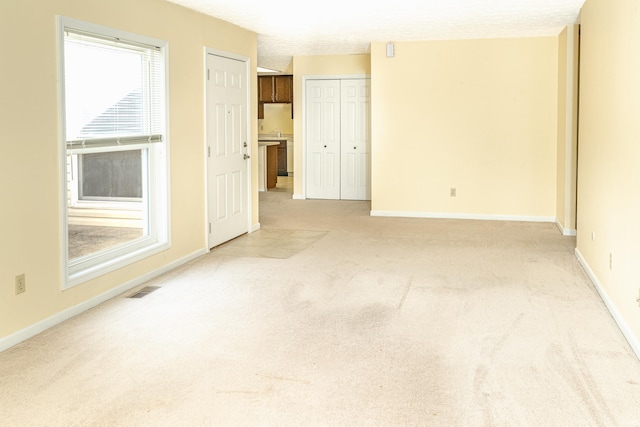 spare room featuring a textured ceiling and light colored carpet