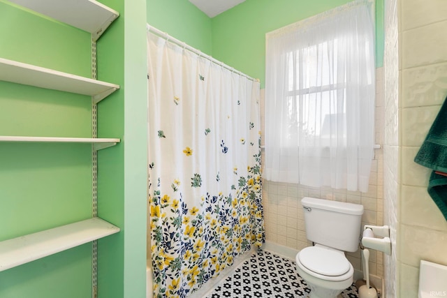 bathroom with toilet, tile patterned floors, a shower with shower curtain, and tile walls