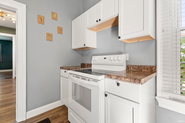 kitchen with white range with electric stovetop, white cabinets, a healthy amount of sunlight, and wood-type flooring