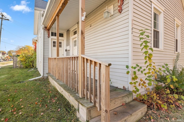 view of exterior entry featuring a lawn and a porch