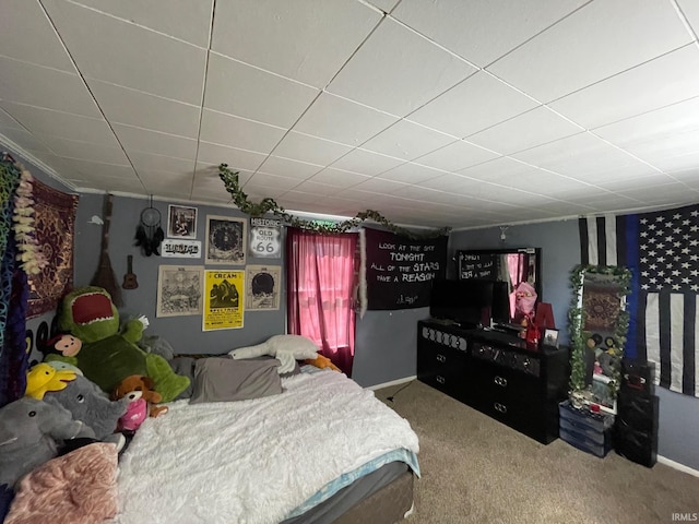carpeted bedroom with baseboards and a drop ceiling