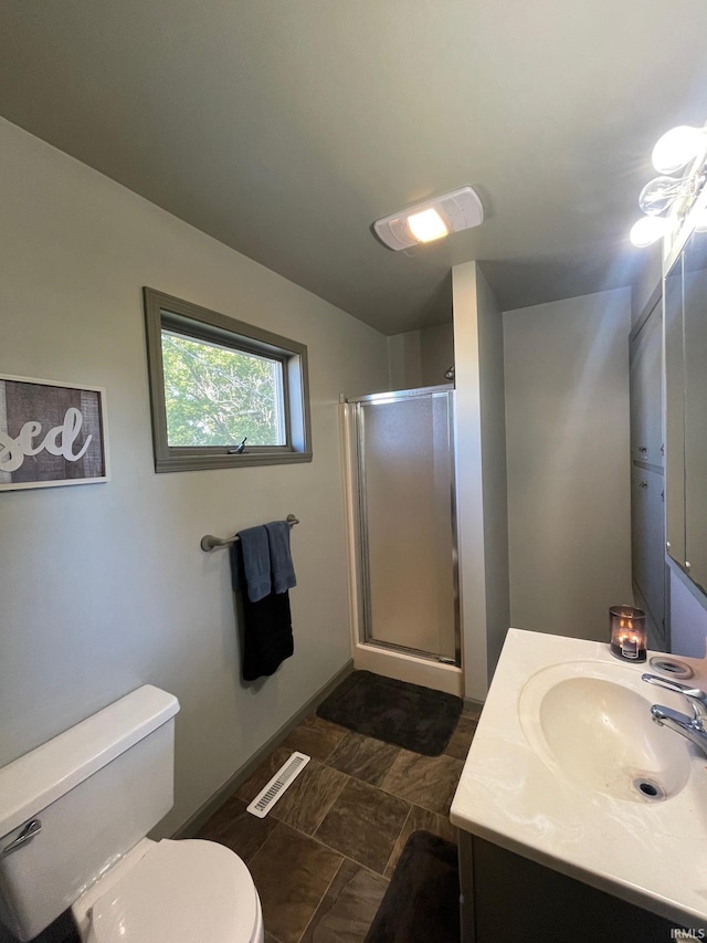 bathroom featuring vanity, toilet, baseboards, a shower stall, and visible vents