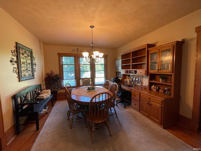 dining room featuring built in desk, a chandelier, and hardwood / wood-style flooring