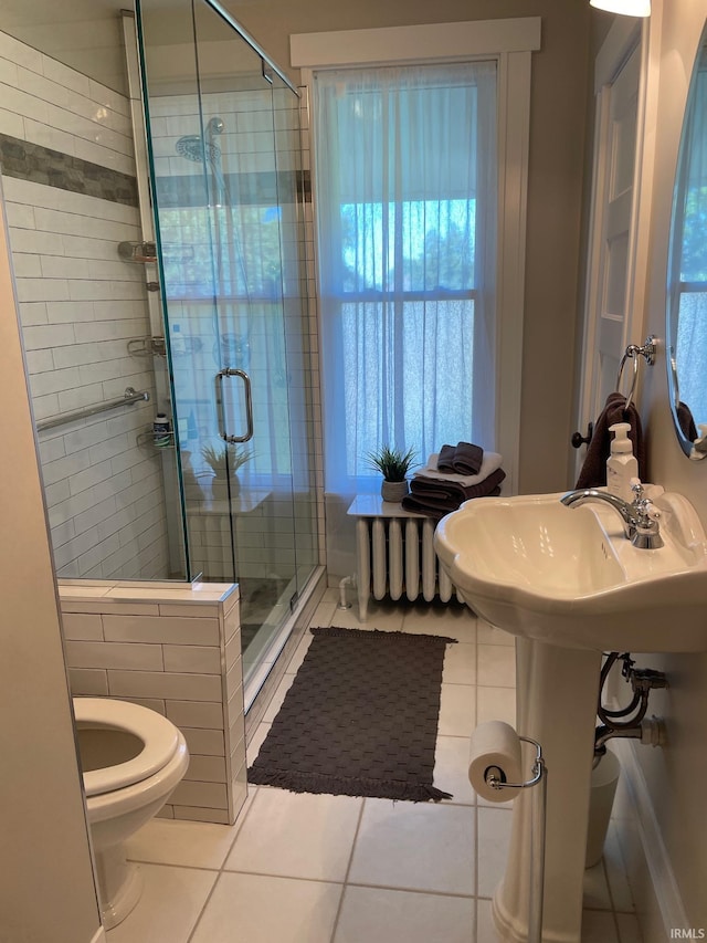 bathroom with toilet, a shower with shower door, and tile patterned flooring