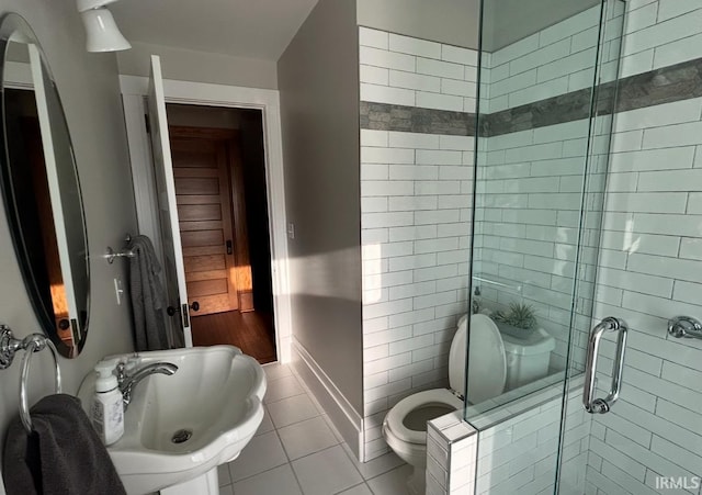 bathroom featuring toilet, tile patterned floors, sink, and an enclosed shower