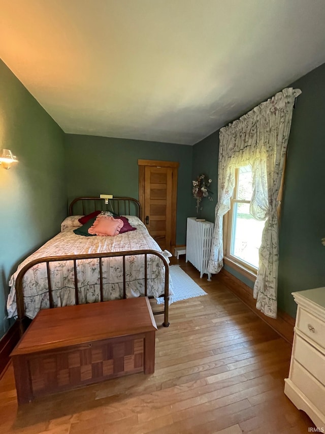 bedroom featuring radiator heating unit and light wood-type flooring