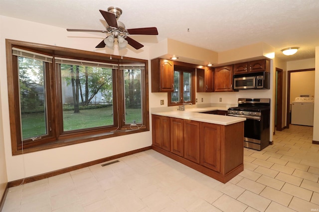 kitchen featuring appliances with stainless steel finishes, washer / clothes dryer, a textured ceiling, kitchen peninsula, and ceiling fan