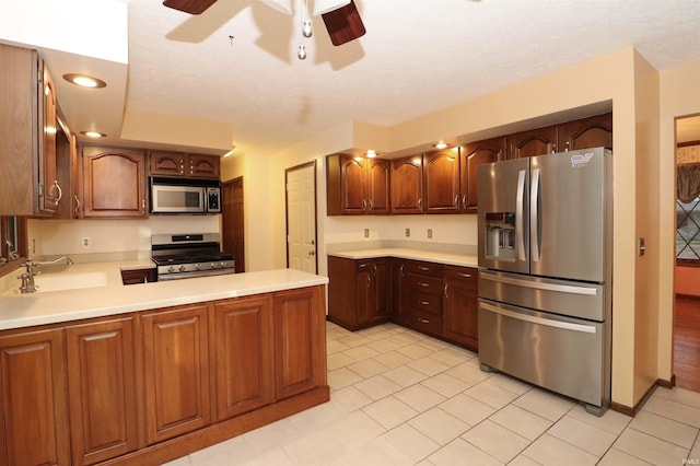 kitchen featuring kitchen peninsula, sink, light tile patterned flooring, appliances with stainless steel finishes, and ceiling fan