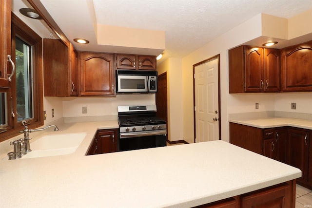 kitchen with sink, kitchen peninsula, stainless steel appliances, and light tile patterned floors