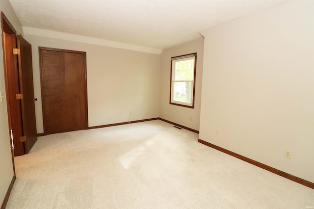 unfurnished bedroom featuring a closet and light colored carpet