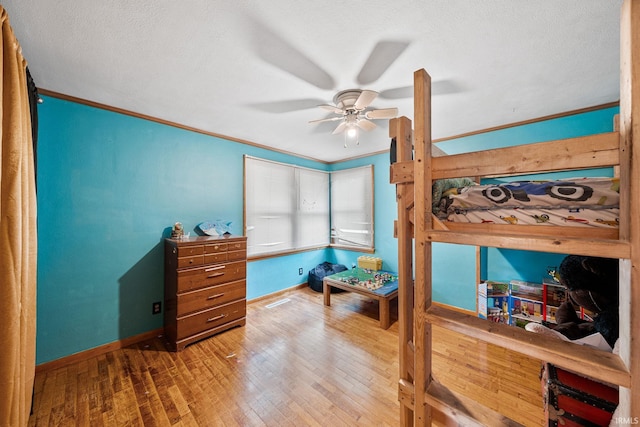 bedroom featuring ceiling fan, hardwood / wood-style flooring, ornamental molding, and a textured ceiling