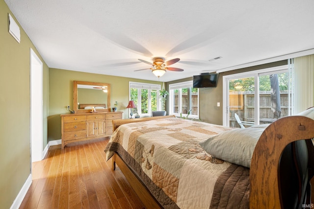 bedroom featuring access to outside, multiple windows, wood-type flooring, and ceiling fan