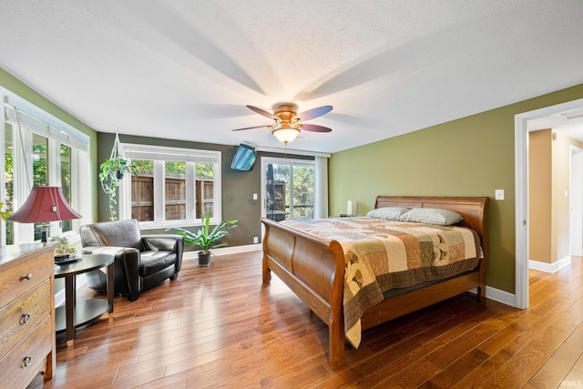 bedroom with a textured ceiling, light wood-type flooring, and ceiling fan