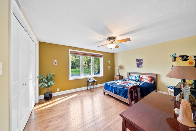 bedroom featuring a closet, a textured ceiling, light wood-type flooring, and ceiling fan