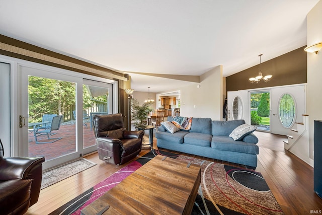 living room featuring a chandelier, vaulted ceiling, wood-type flooring, and a healthy amount of sunlight