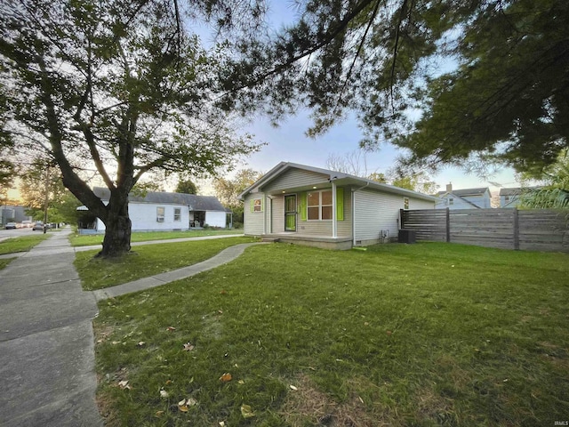 view of home's exterior featuring fence, covered porch, and a lawn