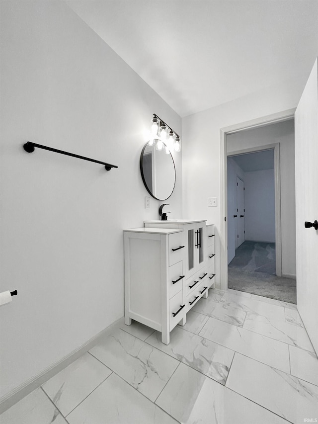 bathroom with marble finish floor, vanity, and baseboards