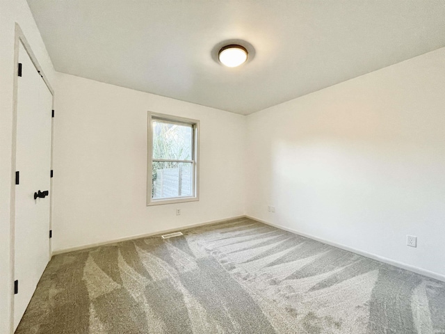 empty room featuring visible vents, carpet flooring, and baseboards