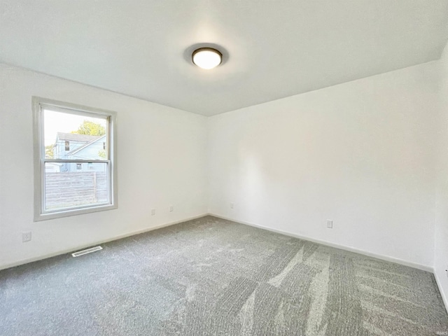 empty room with baseboards, visible vents, and carpet