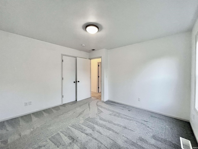 unfurnished bedroom featuring a closet, visible vents, carpet floors, and baseboards