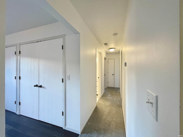 corridor featuring baseboards, visible vents, and carpet flooring