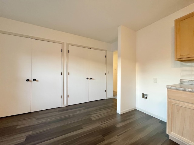 interior space with two closets, baseboards, and dark wood finished floors
