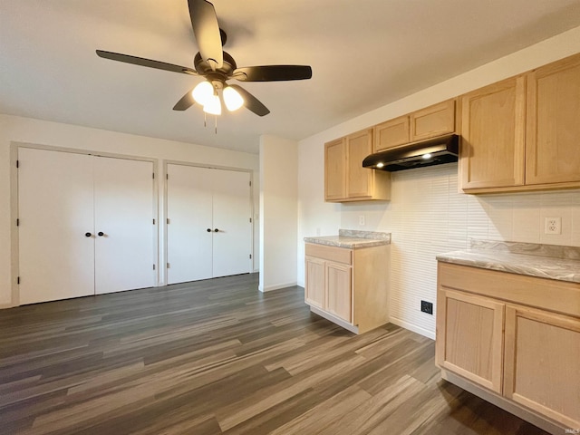 kitchen with dark wood finished floors, light brown cabinetry, under cabinet range hood, light countertops, and ceiling fan
