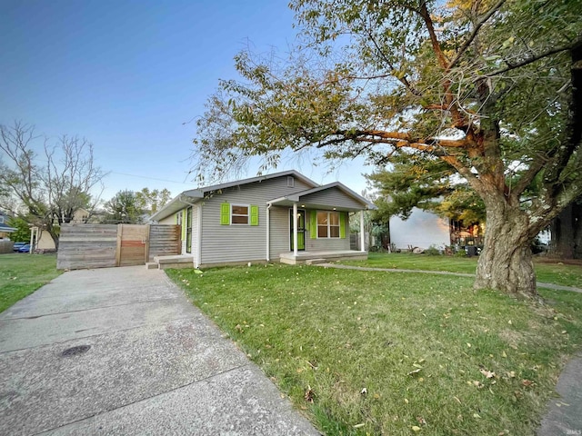 bungalow with fence, a porch, a front lawn, and concrete driveway