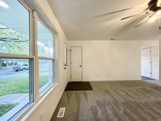 empty room with carpet flooring, visible vents, ceiling fan, and baseboards