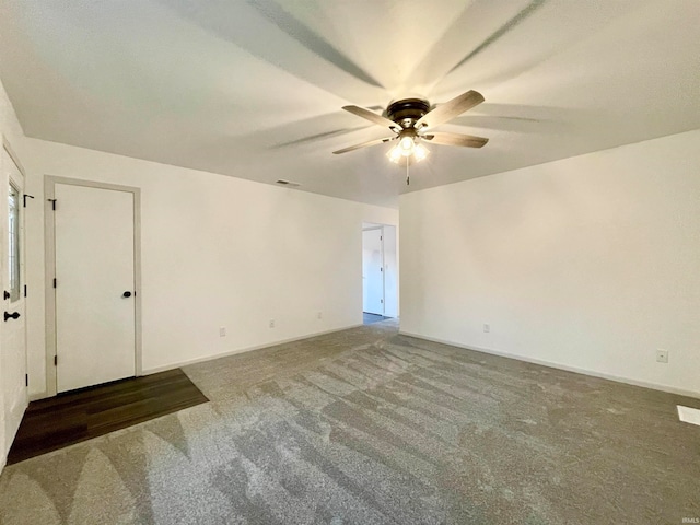 spare room with ceiling fan and dark colored carpet