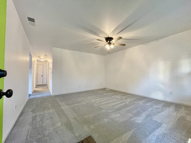 empty room with baseboards, carpet flooring, ceiling fan, and visible vents