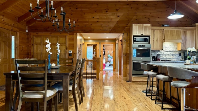 dining room with vaulted ceiling with beams, wooden walls, wooden ceiling, and light hardwood / wood-style floors