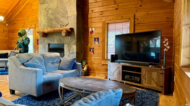 living room with lofted ceiling, hardwood / wood-style floors, wooden ceiling, a stone fireplace, and wooden walls