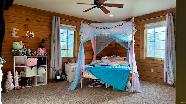 carpeted bedroom with wood walls and ceiling fan