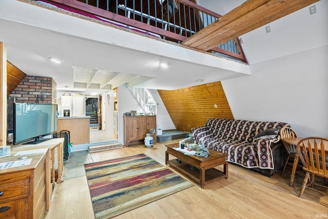 living room with lofted ceiling, light hardwood / wood-style floors, and wood walls