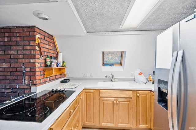 kitchen with light brown cabinets, black electric stovetop, stainless steel refrigerator with ice dispenser, sink, and brick wall