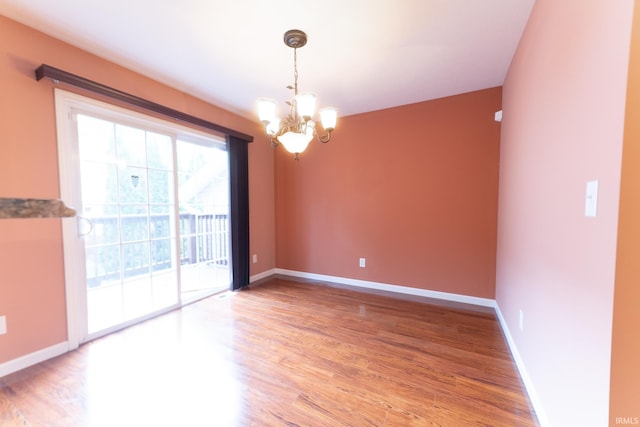 empty room featuring a notable chandelier and wood-type flooring