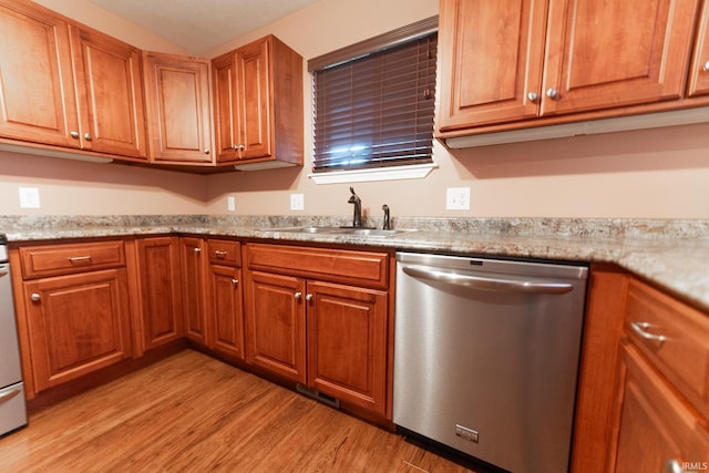 kitchen with light stone counters, stainless steel dishwasher, sink, and light wood-type flooring