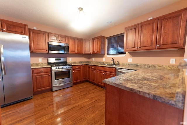 kitchen with light stone counters, appliances with stainless steel finishes, sink, and dark hardwood / wood-style floors