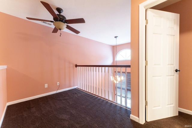 interior space featuring dark carpet and ceiling fan with notable chandelier