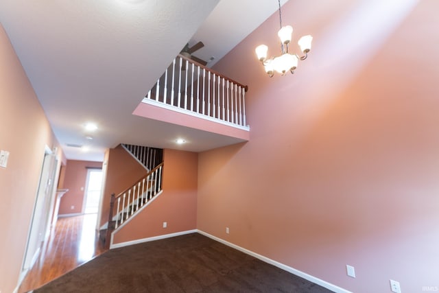 staircase featuring a notable chandelier, carpet flooring, and a towering ceiling