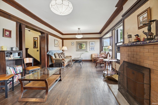 living room featuring crown molding, hardwood / wood-style flooring, and a brick fireplace