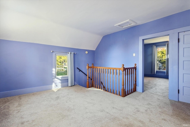 interior space featuring a wealth of natural light, vaulted ceiling, and carpet flooring