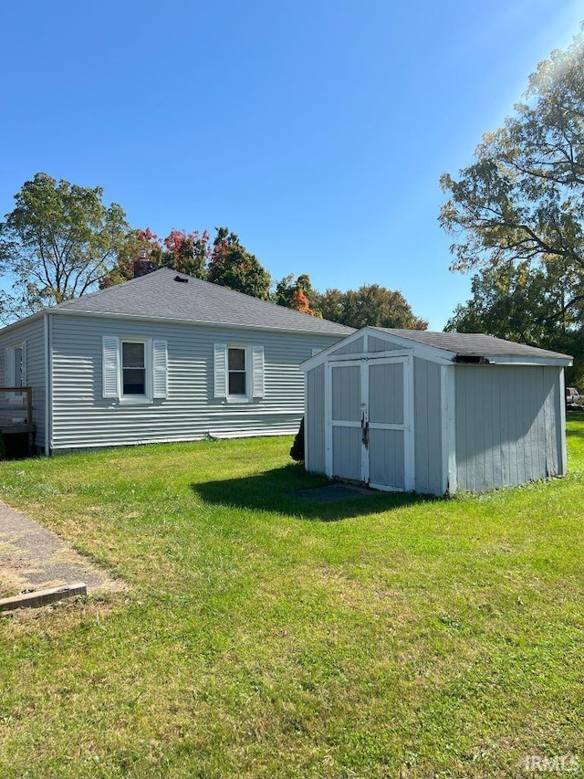 rear view of property featuring a storage unit and a lawn