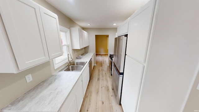 kitchen featuring appliances with stainless steel finishes, sink, white cabinetry, and light hardwood / wood-style flooring